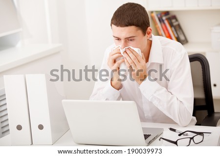 man sneezing while working in office,man having flu