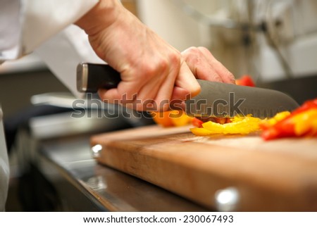 closeup on hands cutting yellow pepper on professional kitchen