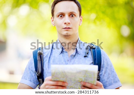 Lost tourist holding map in hands and looking at camera