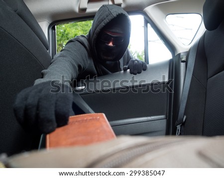Crime concept. Burglar taking wallet from car.