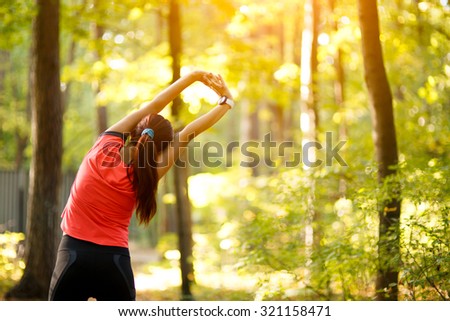 woman exercising in park, stretching hands up