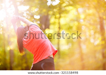 woman exercising in park, stretching hands up