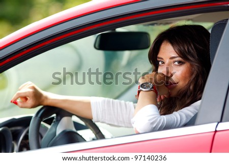 Portrait of young pretty woman in the red car
