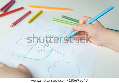 Close-up of childs hand drawing a plane