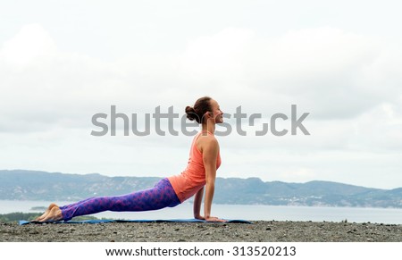 Young woman practicing yoga on top of a mountain - Upward facing dog