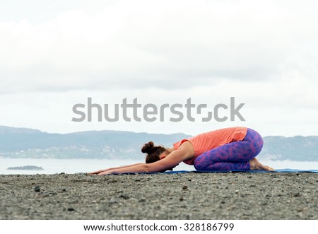 Young woman practicing yoga on top of a mountain - child\'s pose