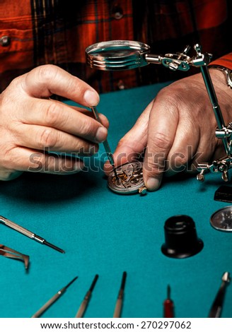 Pocket watch being repaired by senior watch maker, close-up.