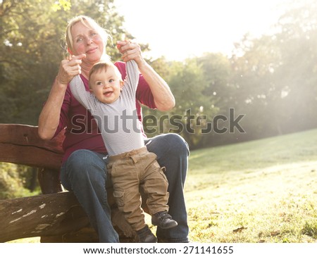 Playful grandmother spending time with his grandson in park on sunny day
