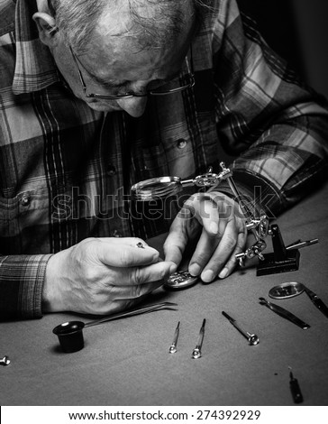 Senior watchmaker repairing an old pocket watch.Black and White