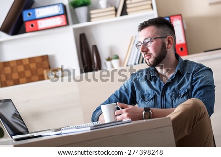Young businessman taking coffee break in his office.