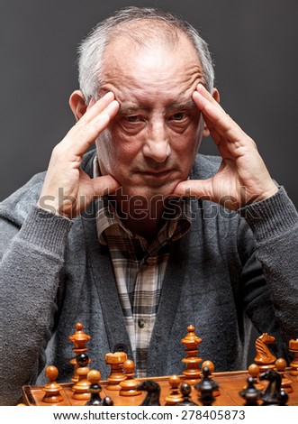 Senior man thinking about his next move in a game of chess