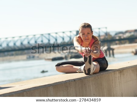 A young female runner stretching her muscles before jogging