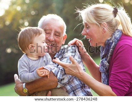 Grandparents with grandson enjoying the sunny day in park.