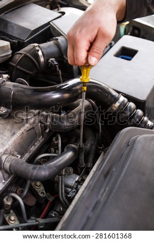 A mechanic checks the oil on a car being repaired