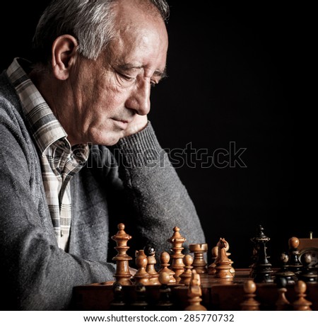 Senior man playing chess and thinking about next move