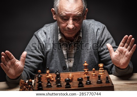 Senior man playing chess and thinking about next move