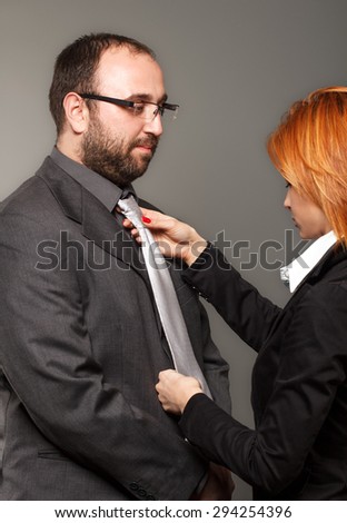 Businesswoman adjusting necktie on businessman