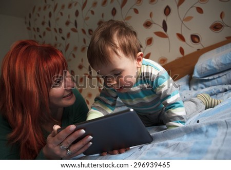 Mother reading bedtime stories to her son on digital tablet