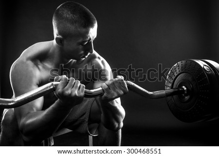 Man with bare chest lift weights on black background. black and white