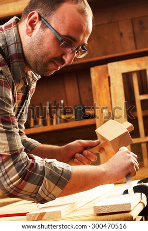 Closeup of a carpenter working with a hammer, chisel and wood carving tools.