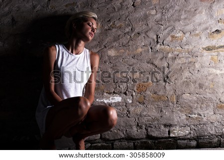 Lonely young woman sitting on the street, looking severely depressed.