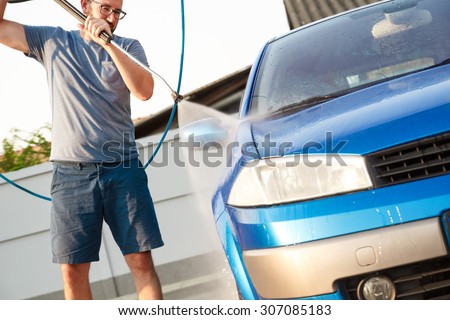 Man washing his car with using a high pressure water jet