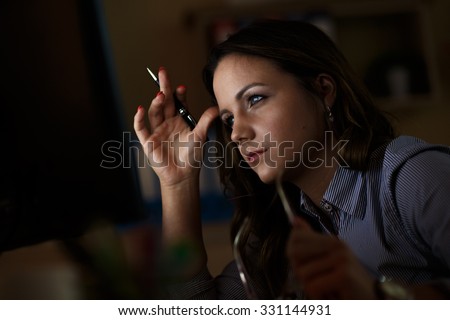 Young female business woman working at home.She works late into the night looking at monitor.
