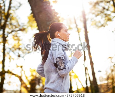 Sporty young woman running in the park and listening to music. Sport lifestyle. Motion blur.