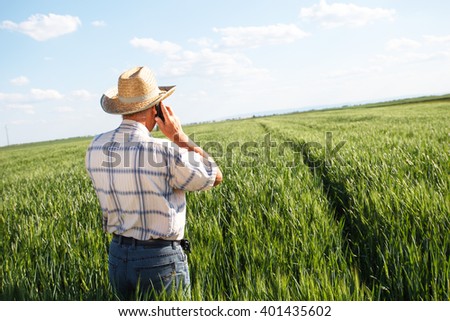 Farmer standing in a wheat field and talking on phone