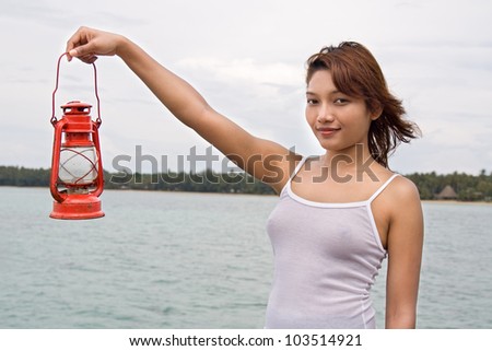 young girl holding a kerosene lantern on seashore