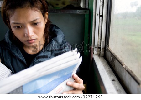 Young woman reading a newspaper on a train