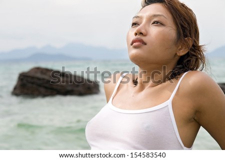 Young girl in wet T-shirt resting on the seashore