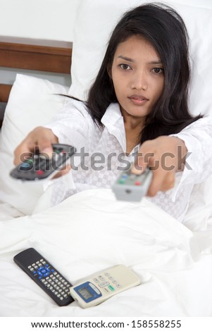 young woman controls the electronics out of bed