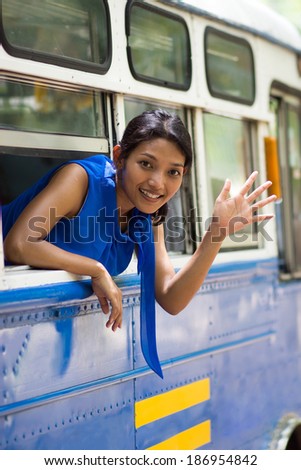 girl waving hand from the bus window
