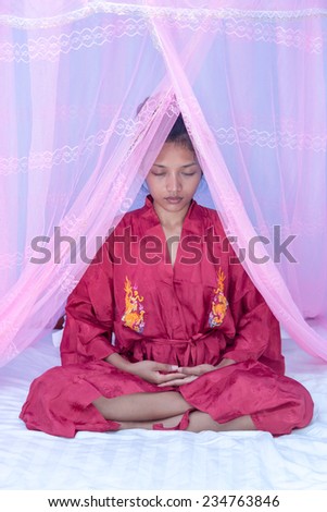 woman doing yoga on bed under a mosquito net