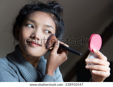 woman applying dry cosmetic on the face using makeup brush