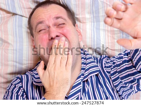 sleepy man yawning in bed