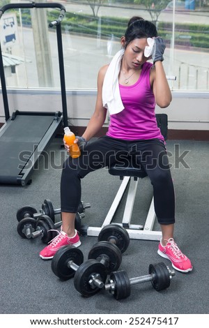 Woman drying her sweat with towel in the gym