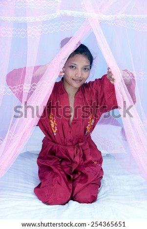 woman on bed under a mosquito net