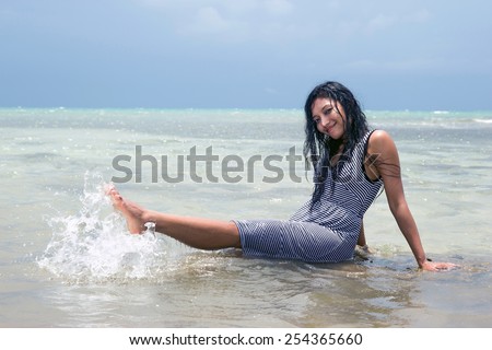Young woman in wet dress playful in the sea