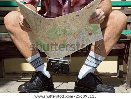 tourist sitting on a bench and looking for a place on the map