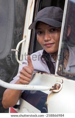 woman truck driver in the car looking out from window with thumb up gesture