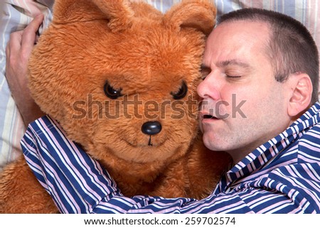 man sleeping in an embrace with a teddy bear
