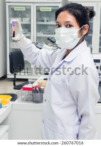 young woman in laboratory controls blood tube