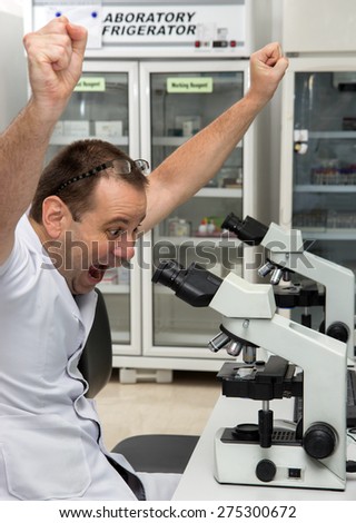 Doctor in laboratory with microscope celebrates success