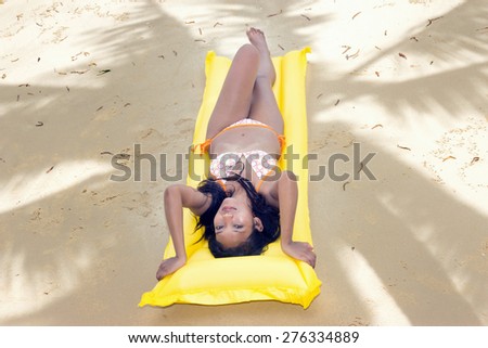 woman resting on the beach under shadow of palm tree