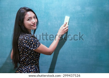 woman in a dress cleans a blackboard