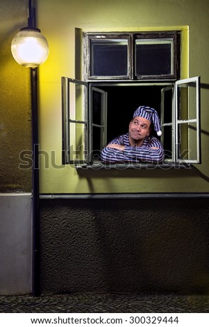 Man in pajamas watching from the window of a street lamp