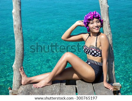 woman in retro swimsuit posing on the mole over sea