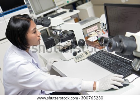 woman working in a laboratory with microscope and computer